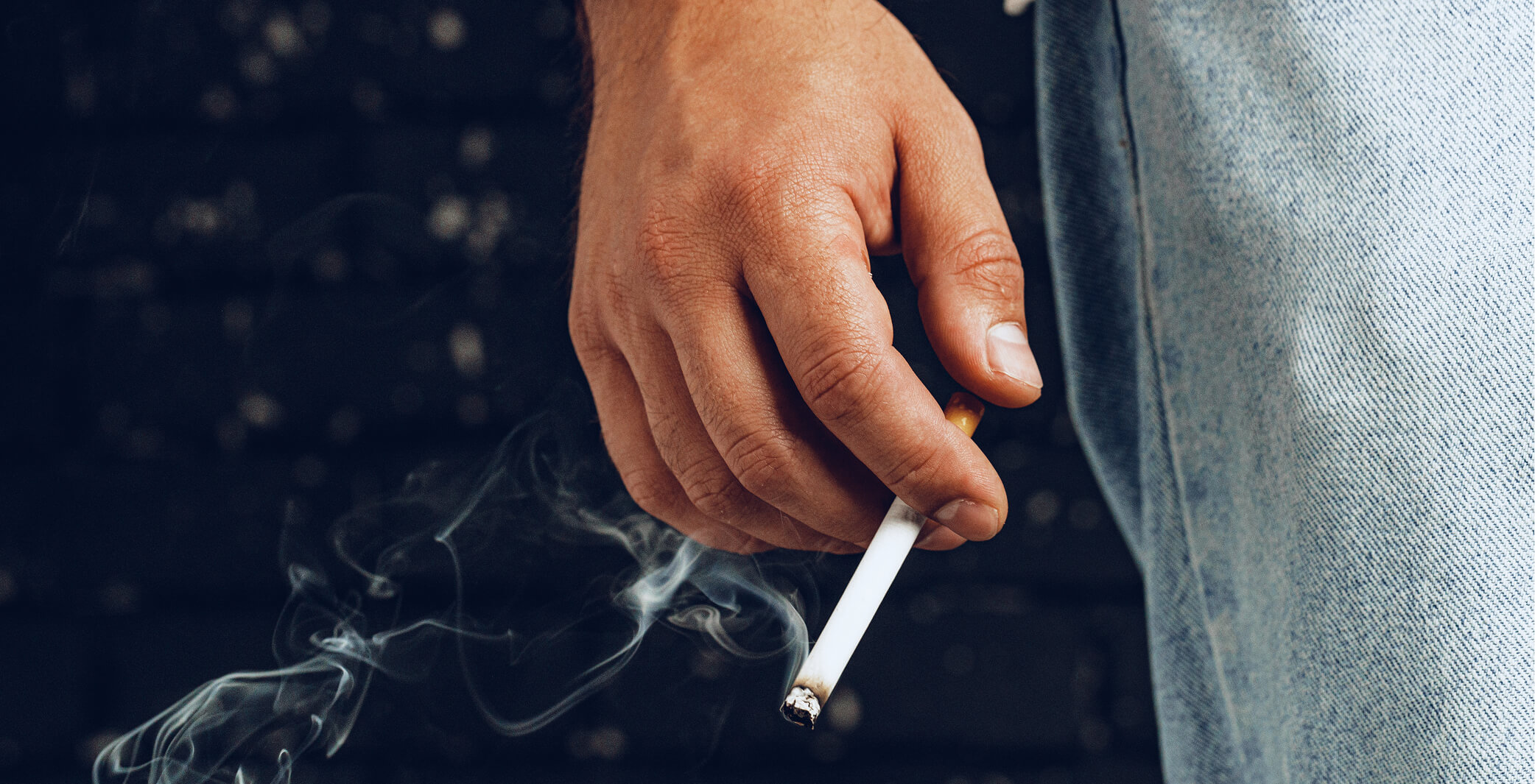 male-hand-holding-lit-cigarette-against-black-back-2025-02-24-16-17-51-utc (1)