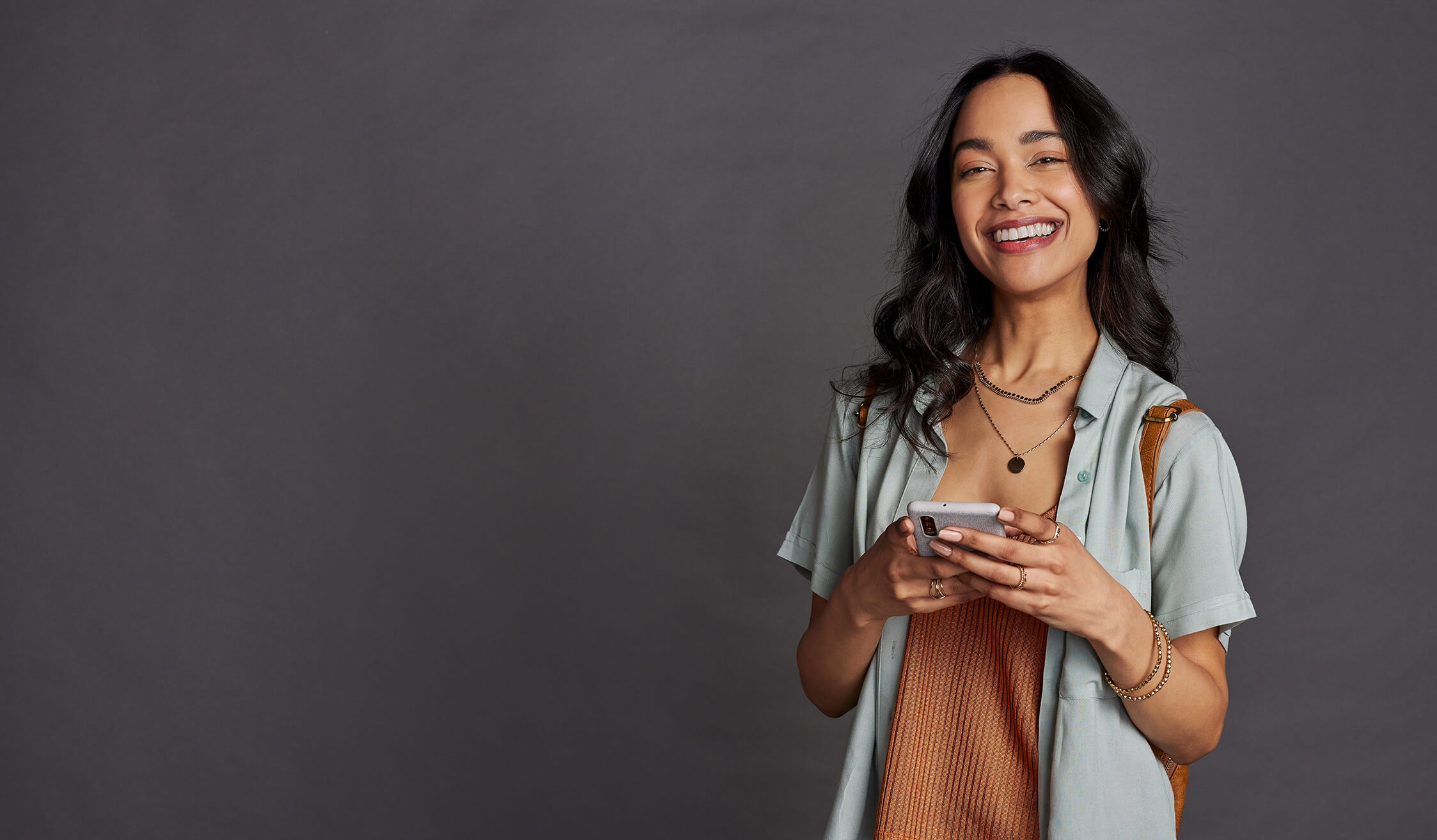 multiethnic-young-woman-using-smartphone-on-grey-w-2023-11-27-05-33-43-utc (1)